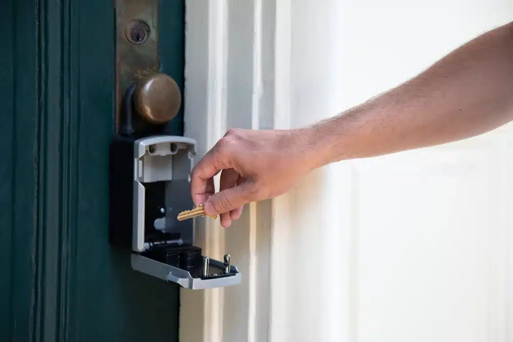 A hand taking the key from a lockbox on the front door of a house for sale