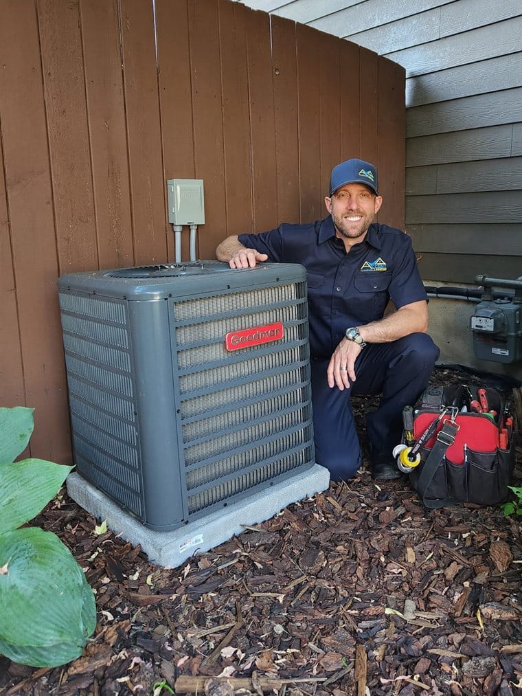 Ben from Accent Plumbing and Heating beside an air conditioning unit he has installed at a Calgary home