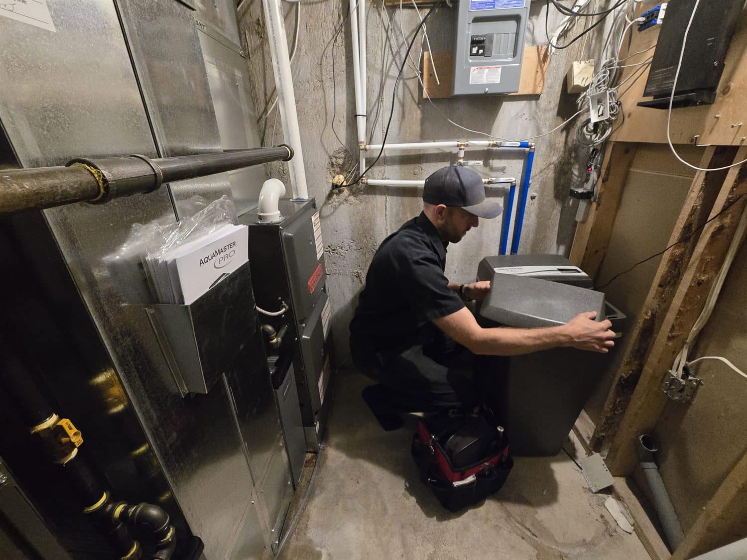 Ben from Accent Plumbing and Heating fitting a water softener in a Calgary basement