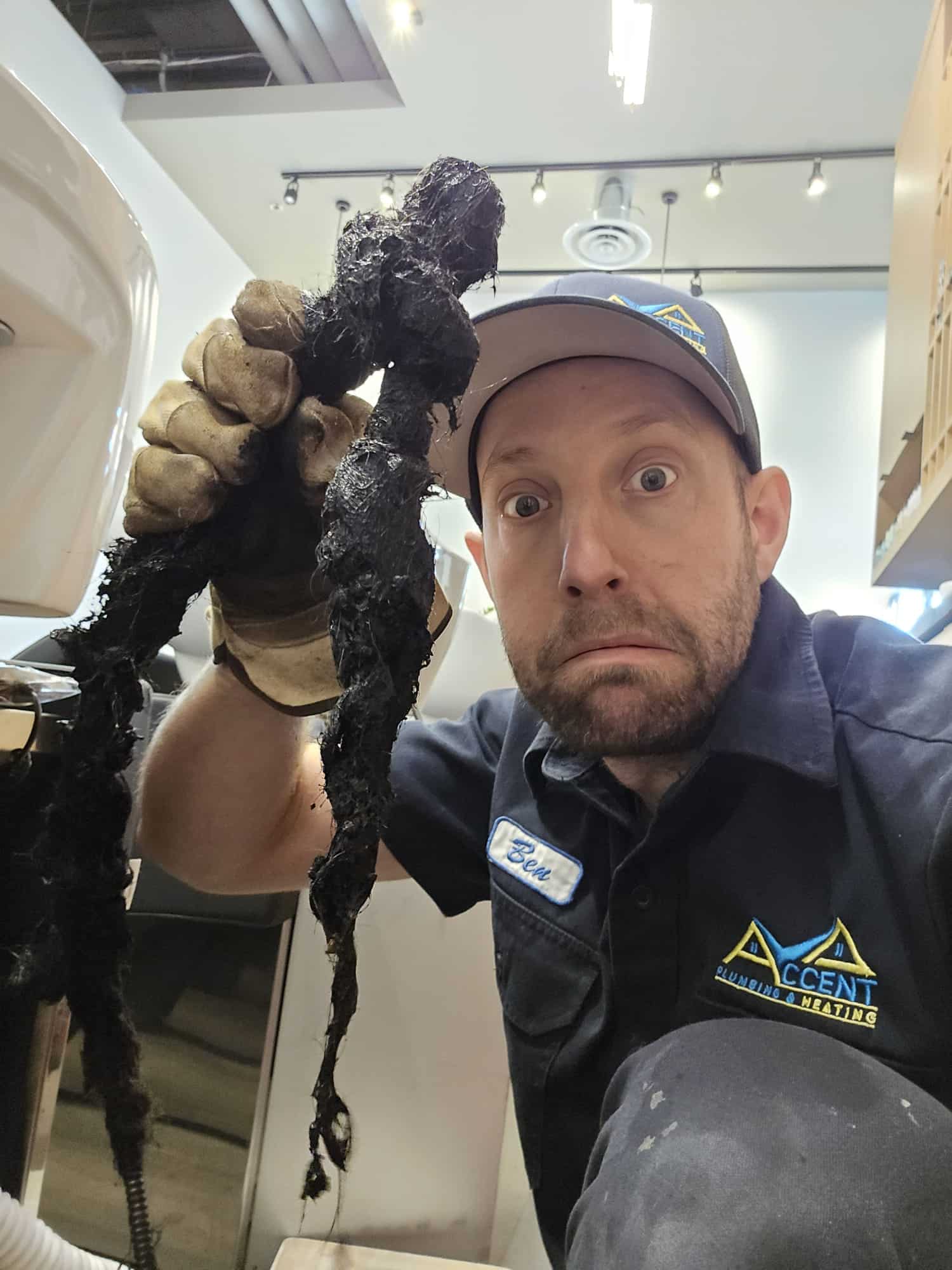 Ben from Accent Plumbing and Heating holding a hair clog pulled out of a blocked drain
